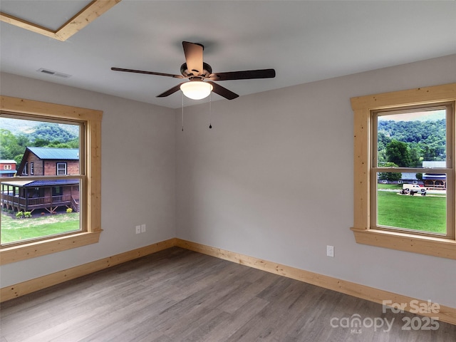 empty room featuring visible vents, light wood-style flooring, ceiling fan, and baseboards