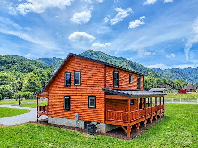 view of property exterior with cooling unit, a yard, covered porch, fence, and a mountain view