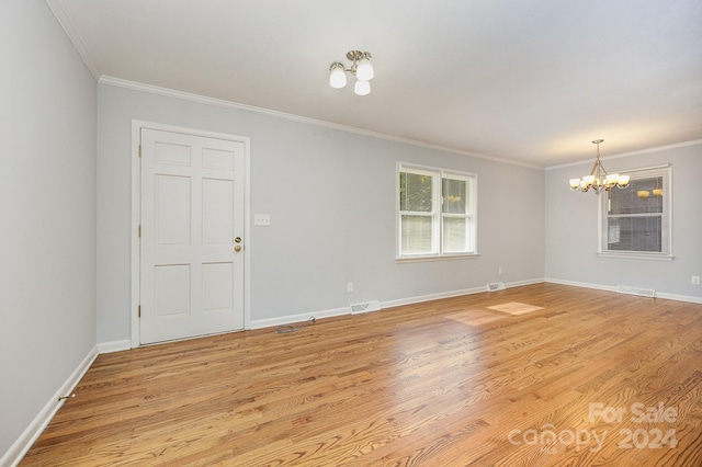 empty room with light hardwood / wood-style floors, crown molding, and a notable chandelier