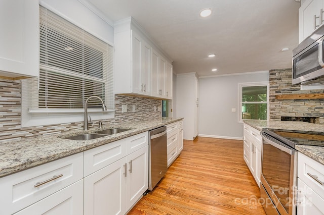 kitchen featuring sink, tasteful backsplash, appliances with stainless steel finishes, white cabinets, and light wood-type flooring