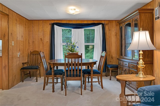 dining room featuring light colored carpet and wooden walls