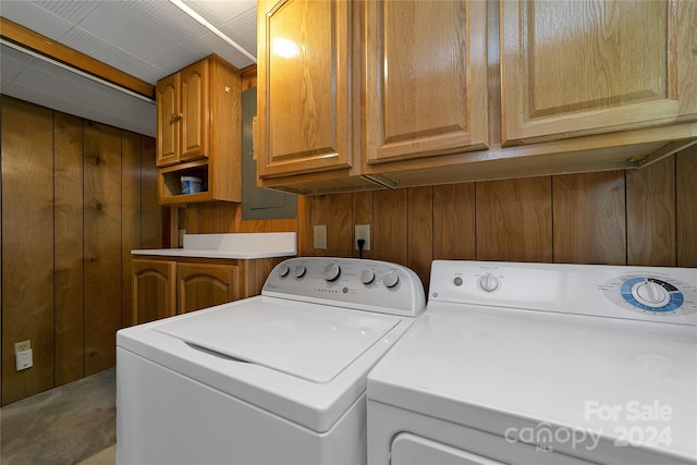 laundry room featuring washer and clothes dryer, wooden walls, and cabinets