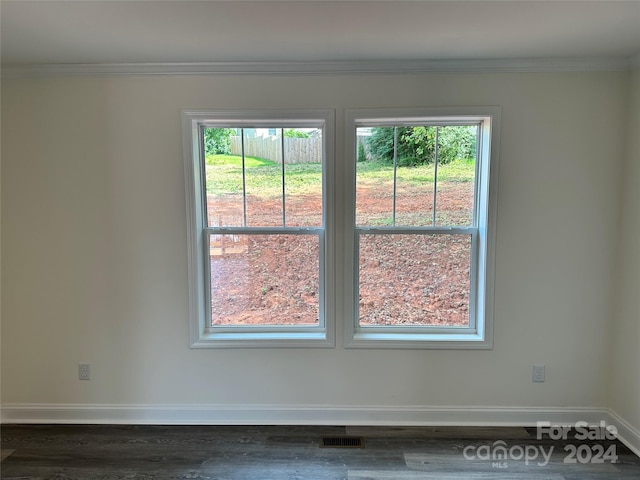 unfurnished room featuring baseboards, visible vents, dark wood-style flooring, and crown molding