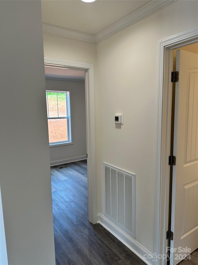 corridor featuring dark wood-type flooring, visible vents, crown molding, and baseboards