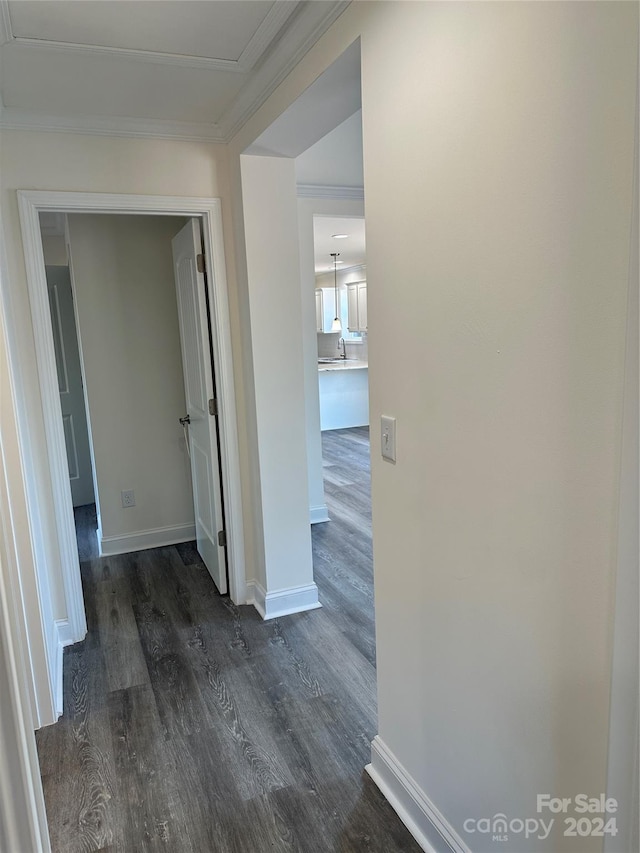 hallway featuring baseboards, ornamental molding, and dark wood finished floors