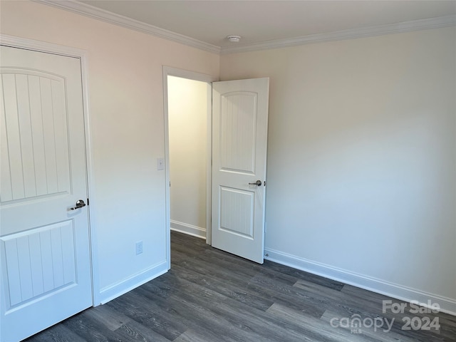 unfurnished bedroom featuring baseboards, dark wood-style flooring, and crown molding