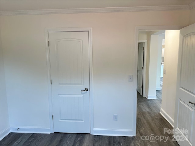 unfurnished bedroom with ornamental molding, dark wood finished floors, and baseboards