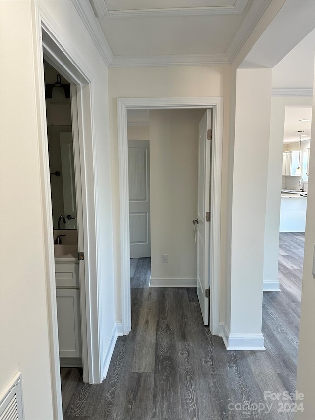 corridor with ornamental molding, visible vents, baseboards, and wood finished floors