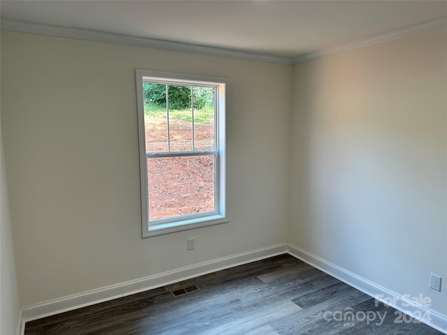 empty room featuring crown molding, dark wood finished floors, visible vents, and baseboards