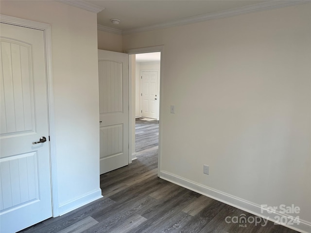 empty room featuring baseboards, dark wood finished floors, and crown molding