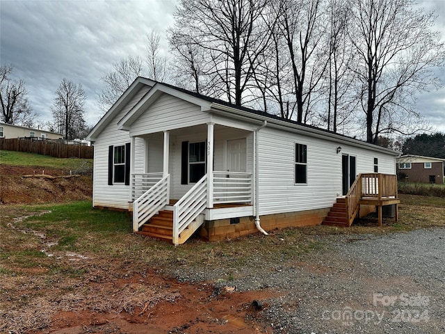 view of front of property with covered porch, fence, and crawl space