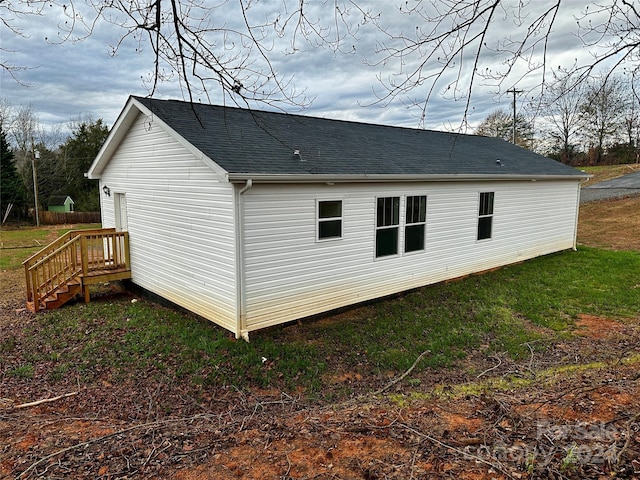 back of house featuring a yard and a shingled roof