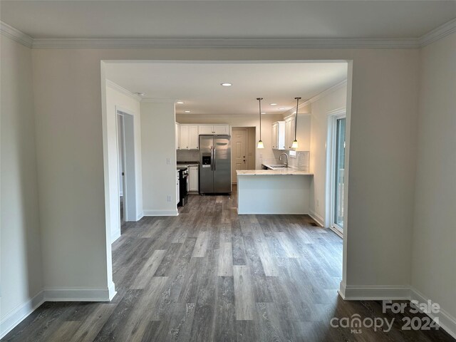 kitchen with sink, stainless steel fridge with ice dispenser, decorative backsplash, ornamental molding, and white cabinetry