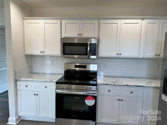 kitchen with white cabinetry, stainless steel appliances, crown molding, decorative backsplash, and hardwood / wood-style flooring