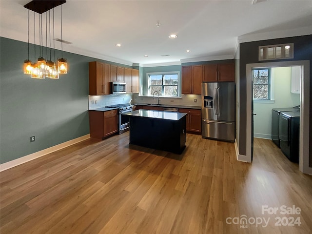 kitchen with stainless steel appliances, light hardwood / wood-style flooring, independent washer and dryer, a center island, and hanging light fixtures