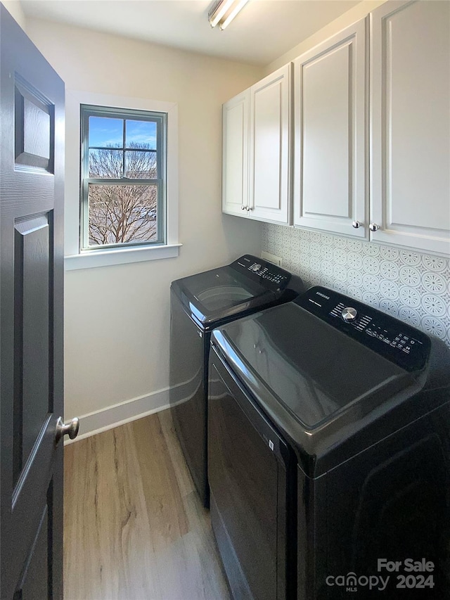 washroom with washer and clothes dryer, cabinets, and light wood-type flooring