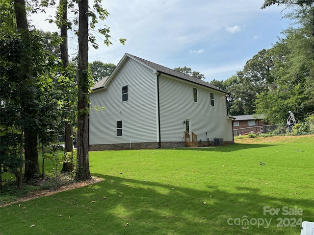 view of side of home featuring central air condition unit and a yard