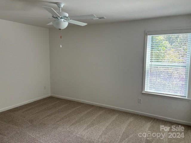 carpeted spare room featuring ceiling fan