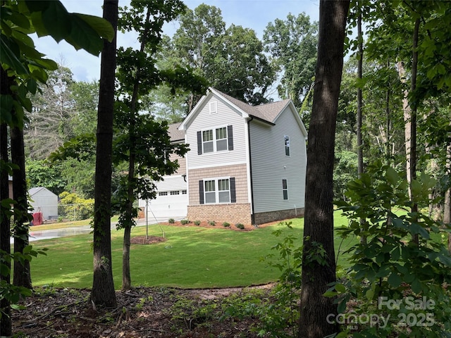 view of side of home with a garage, brick siding, a lawn, and concrete driveway