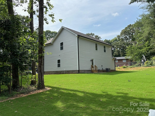 view of side of property featuring central AC and a yard