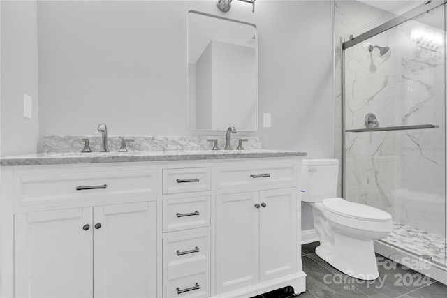 bathroom featuring a shower with shower door, vanity, tile patterned flooring, and toilet