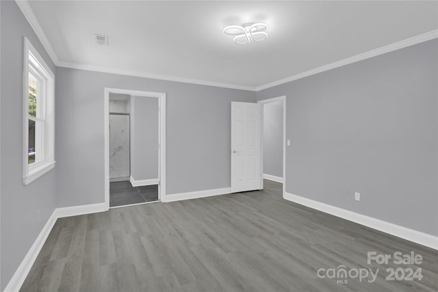 unfurnished bedroom with ornamental molding, hardwood / wood-style floors, and ensuite bath