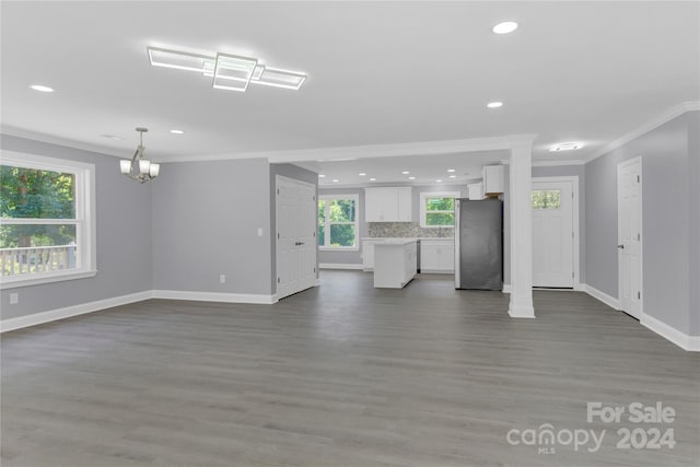 unfurnished living room with dark hardwood / wood-style floors, ornamental molding, and a chandelier