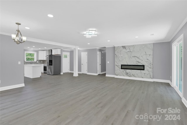 unfurnished living room featuring a high end fireplace, plenty of natural light, crown molding, and light hardwood / wood-style floors