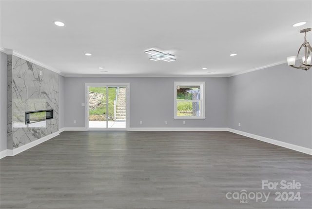 unfurnished living room featuring a chandelier, dark hardwood / wood-style flooring, crown molding, and a premium fireplace