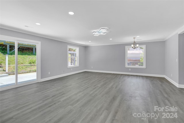 spare room featuring ornamental molding, a healthy amount of sunlight, hardwood / wood-style flooring, and a notable chandelier