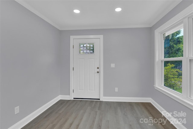 foyer entrance with light wood-type flooring, ornamental molding, and plenty of natural light