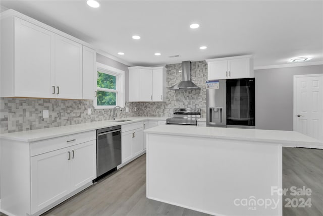 kitchen featuring tasteful backsplash, wall chimney range hood, a kitchen island, appliances with stainless steel finishes, and white cabinets