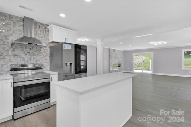 kitchen with white cabinetry, appliances with stainless steel finishes, backsplash, wall chimney exhaust hood, and a center island