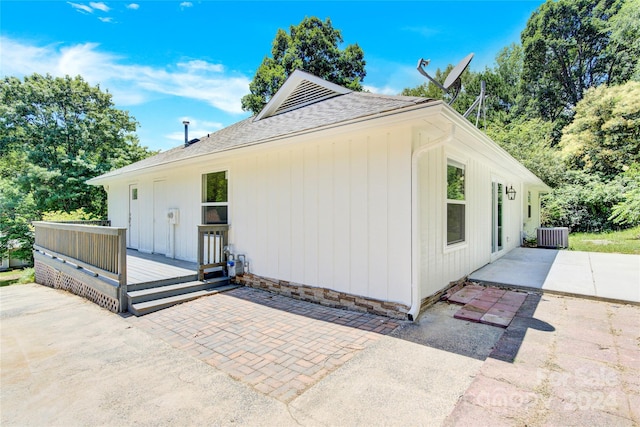 view of side of home featuring central air condition unit, a wooden deck, and a patio