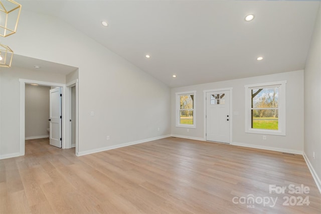 unfurnished living room featuring a healthy amount of sunlight, light wood-type flooring, and vaulted ceiling