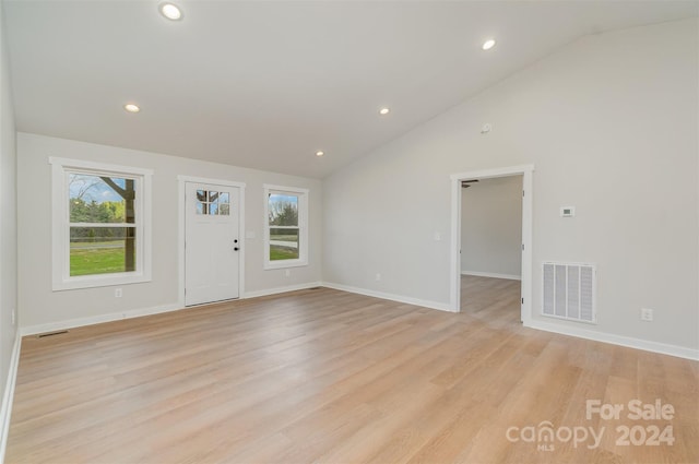 unfurnished living room with light wood-type flooring and high vaulted ceiling