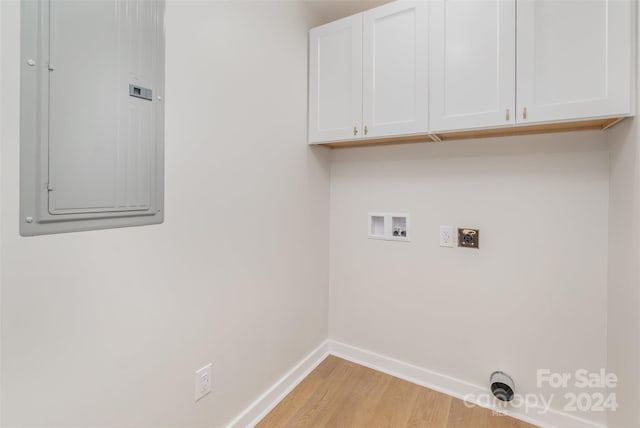 clothes washing area with cabinets, electric dryer hookup, electric panel, hookup for a washing machine, and light wood-type flooring