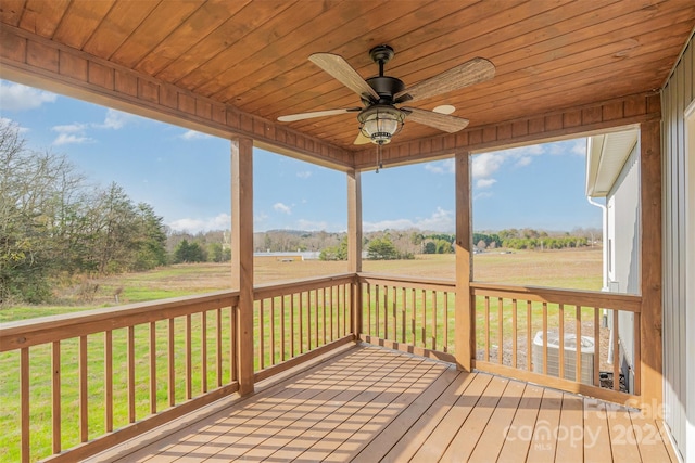 wooden terrace with a lawn, ceiling fan, and a rural view