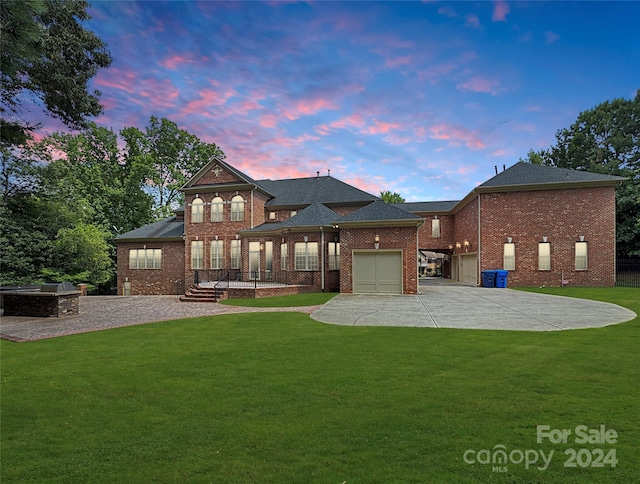 back house at dusk featuring a garage and a yard