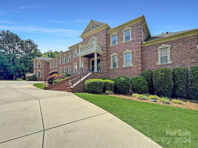 view of front of property featuring a balcony and a front yard