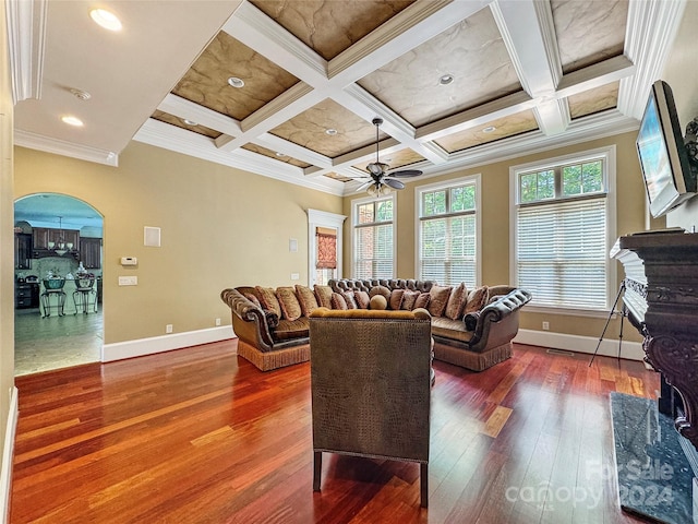 living room featuring ceiling fan, beam ceiling, dark hardwood / wood-style floors, ornamental molding, and coffered ceiling