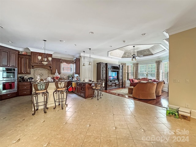 kitchen with pendant lighting, a center island, double oven, ornamental molding, and a breakfast bar