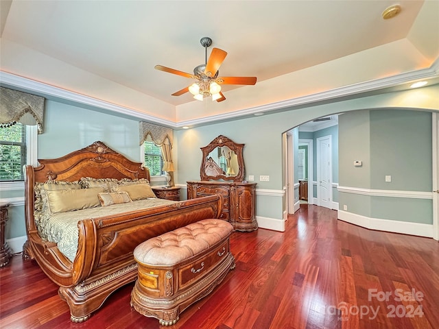 bedroom with crown molding, dark hardwood / wood-style flooring, ceiling fan, and a raised ceiling