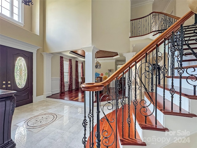 foyer entrance with decorative columns, a high ceiling, and ornamental molding