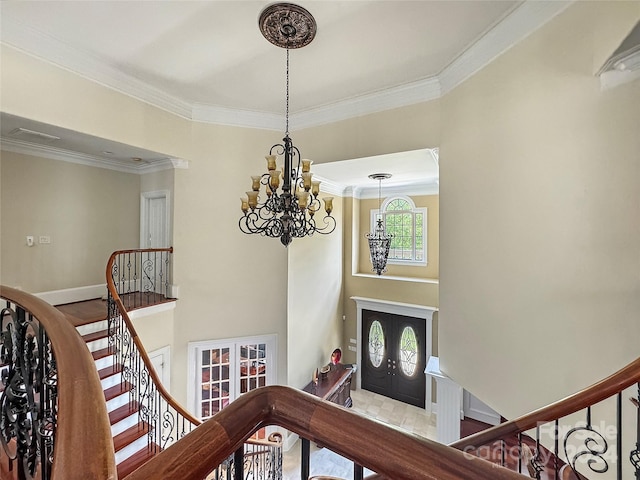 entryway featuring french doors, light hardwood / wood-style flooring, ornamental molding, and a notable chandelier