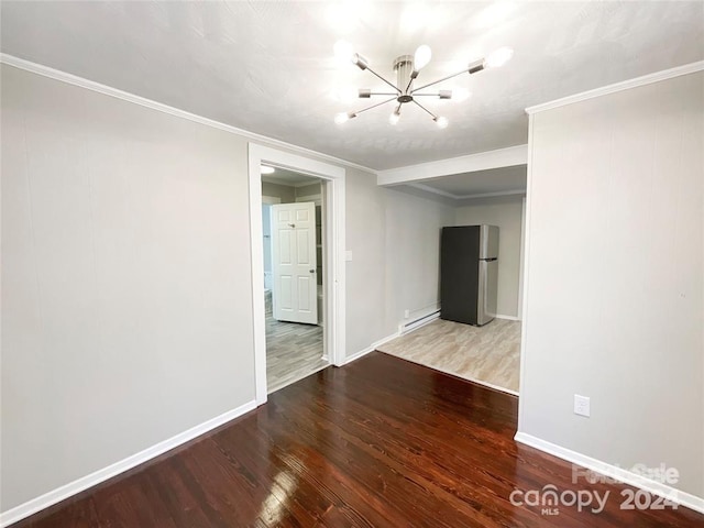 unfurnished room featuring a baseboard radiator, wood-type flooring, crown molding, and an inviting chandelier