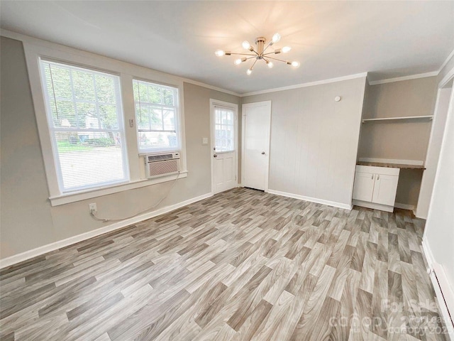 empty room with a notable chandelier, cooling unit, light hardwood / wood-style flooring, and crown molding