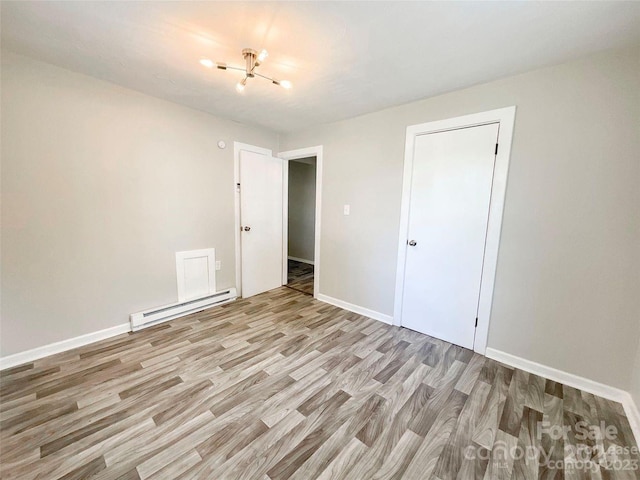 unfurnished bedroom featuring a closet, light hardwood / wood-style flooring, and a baseboard radiator