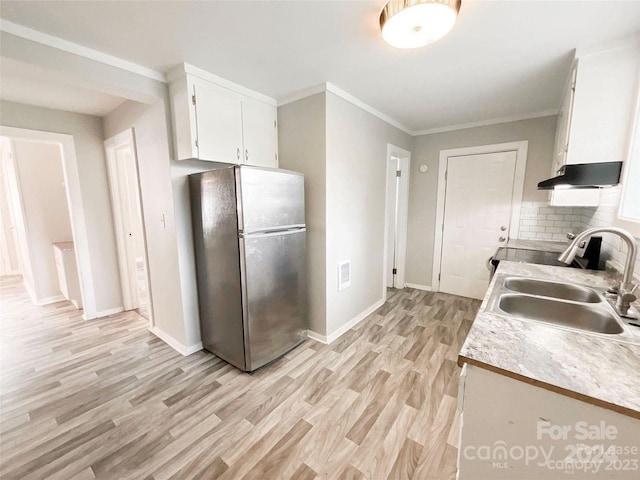 kitchen featuring crown molding, white cabinetry, sink, light hardwood / wood-style flooring, and stainless steel fridge