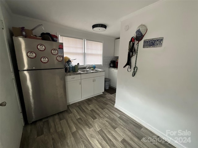 kitchen with white cabinetry, dark hardwood / wood-style flooring, sink, stainless steel refrigerator, and crown molding